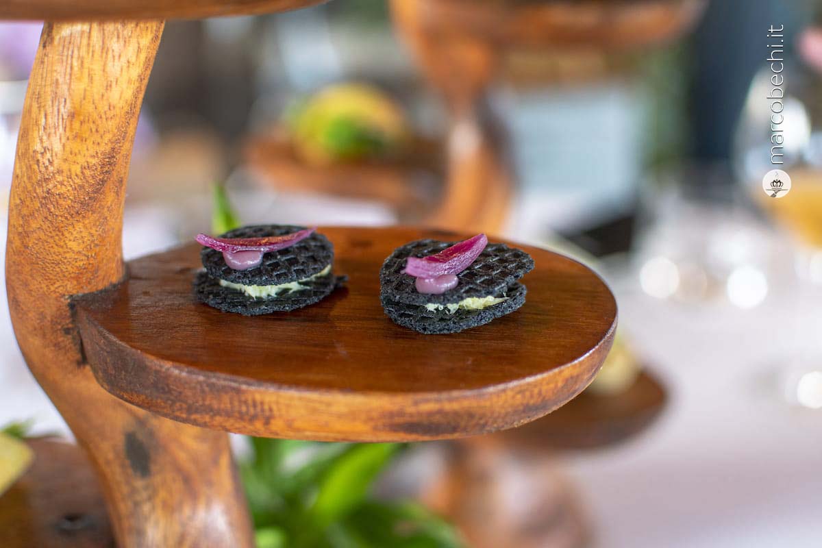 Tra le amuse bouche ecco il Wafer nero alle arachidi, baccalà all'olio di nocciola e cipolla