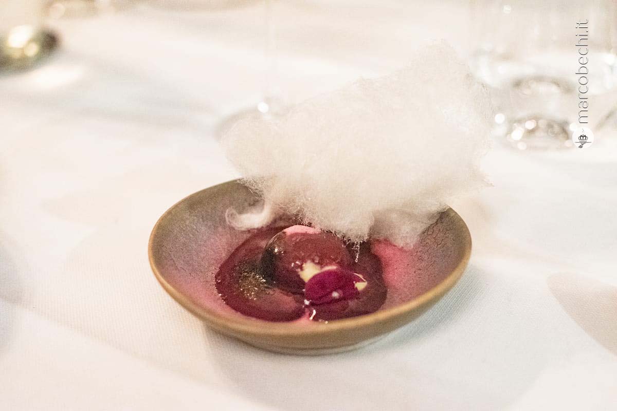 Bottone di lampone con nuvola di zucchero, salsa di frutti di bosco e polvere di lampone