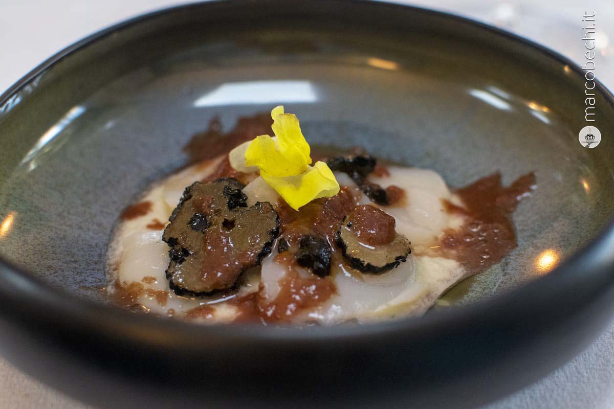 Carpaccio di capasanta su crema di scalogno, nocciole, tartufo nero, riduzione di aglio nero e granita di fragola