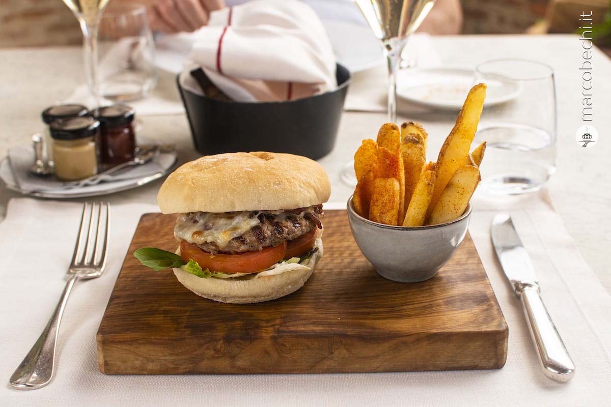 Hamburger di manzo con pecorino fondente, cipolla, pomodori, cuor di lattuga e salsa Juan servito con patate alla paprika